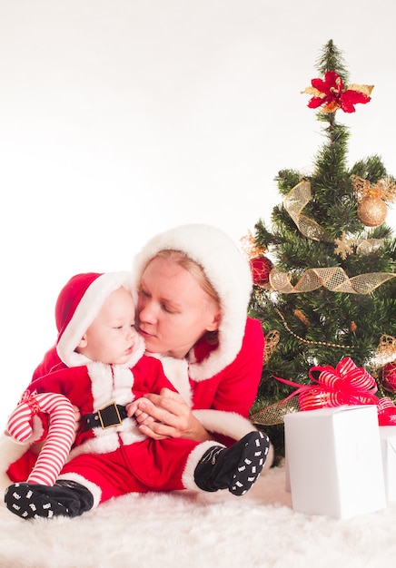 Bebê e mãe de Natal sob o pinheiro isolado