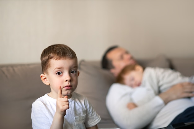 Bebê e pai dormindo no sofá durante o dia - conceito de dia das crianças e cuidado dos pais com foco nas mãos