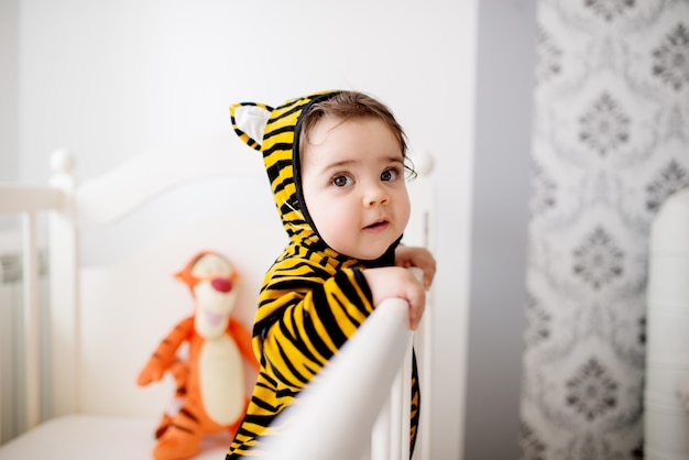 Bebê em traje de tigre. Se divertindo no berço.