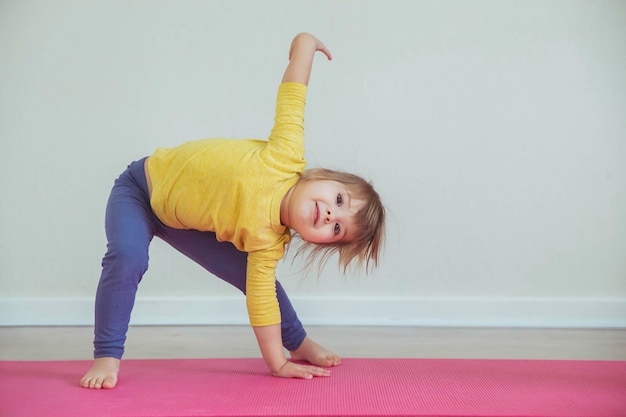 Bebé encantador haciendo yoga en casa. lugar para texto