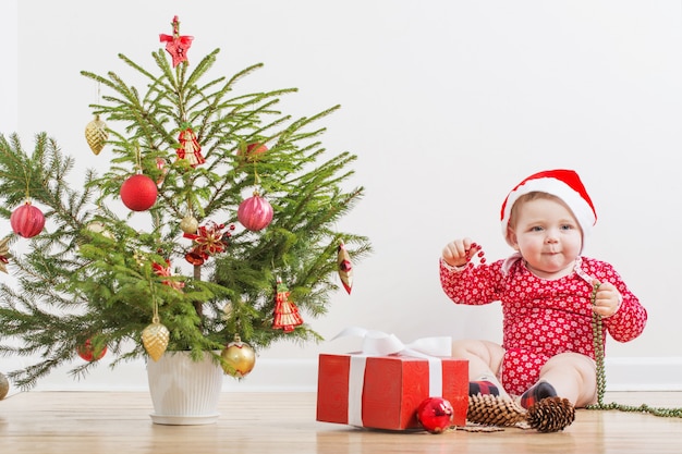 Bebê engraçado com pouco de abeto de natal em casa