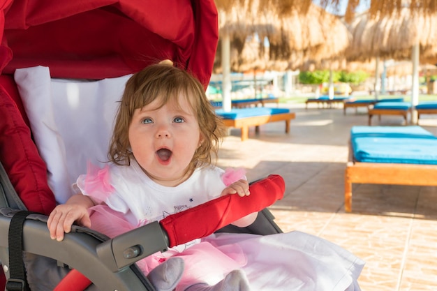 Bebê engraçado sentado em um carrinho em um dia ensolarado no resort