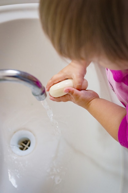 El bebé se enjabona las manos y sale agua del grifo.