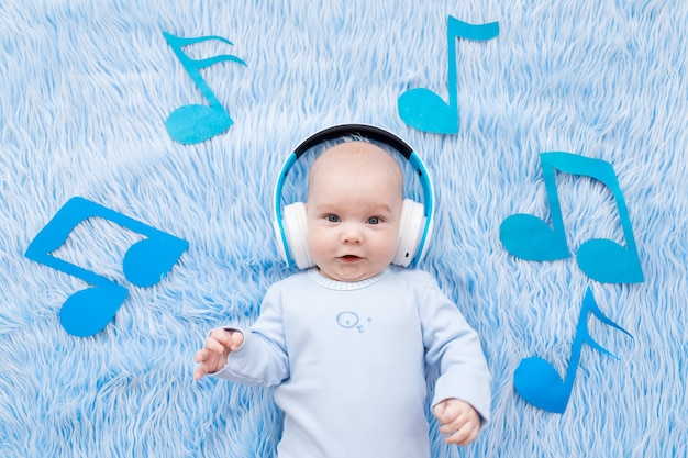 Foto bebé escuchando música con auriculares sobre una alfombra azul