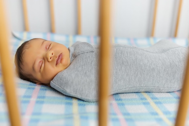 El bebé está acostado en un capullo en la cuna. Duerme dulcemente y sueña.