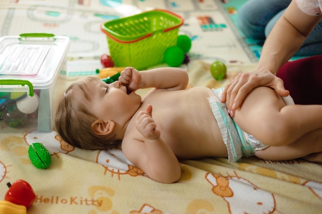 Un bebé está acostado sobre una manta con la palabra hello kitty.