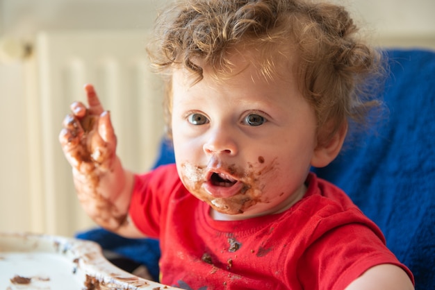 El bebé está comiendo un pastel de chocolate.