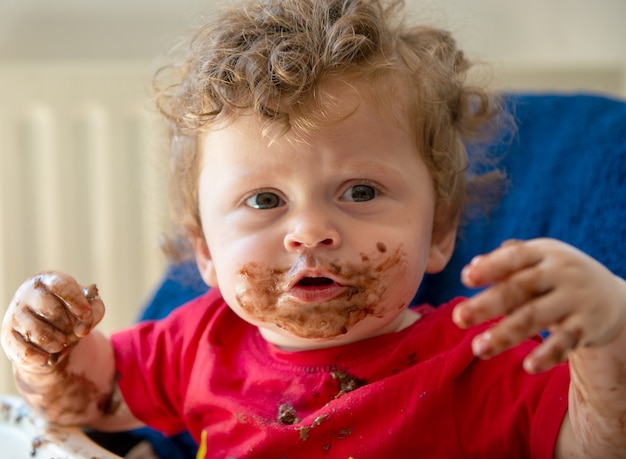 El bebé está comiendo un pastel de chocolate.