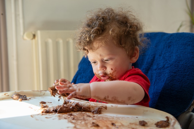 El bebé está comiendo un pastel de chocolate.