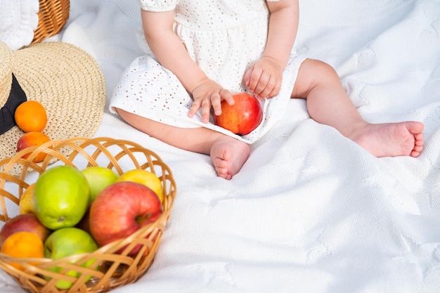 Un bebé está sentado en una cama con manzanas y manzanas.