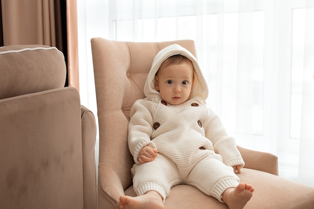 El bebé está sentado en una silla con un mono tejido