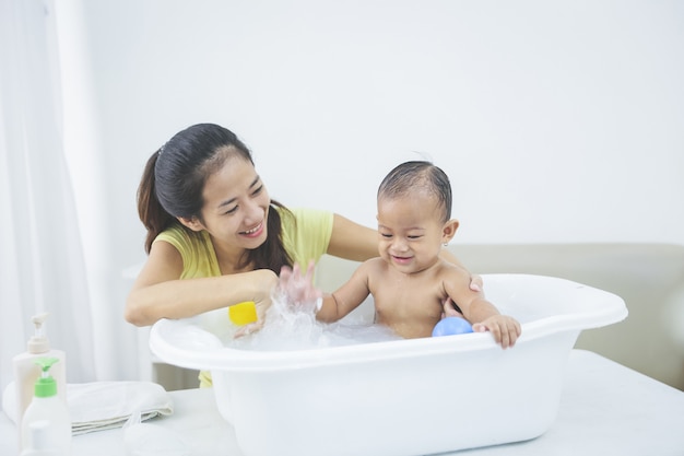 El bebé está siendo bañado por su madre.