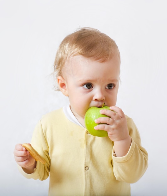 Un bebé está tratando de comerse su primera merienda. Espacio libre para un texto