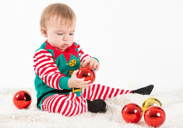 Bebê fantasiado de elfo pegando bolas de natal