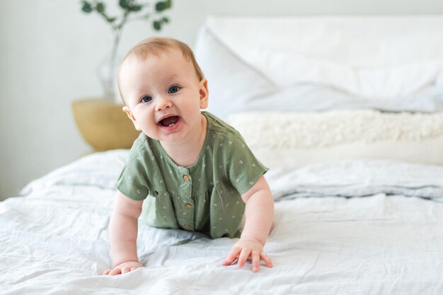 Bebê feliz, bonita, menina recém-nascida com rosto sorridente rastejando na cama no quarto, bebê descansando