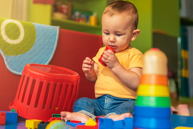 Foto bebê feliz brincando com blocos de brinquedo no jardim de infância.