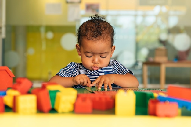 Foto bebê feliz brincando com blocos de brinquedo no jardim de infância.