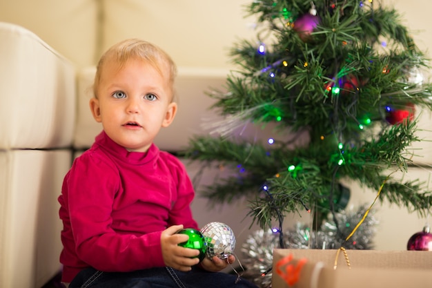 Bebé feliz cerca del árbol de Navidad