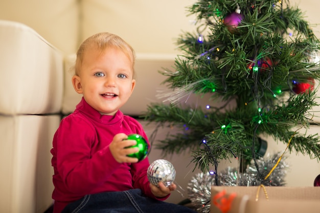 Bebé feliz cerca del árbol de Navidad