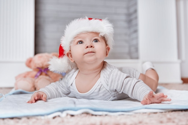 Bebê feliz com chapéu de Papai Noel na véspera de Natal. o conceito de natal