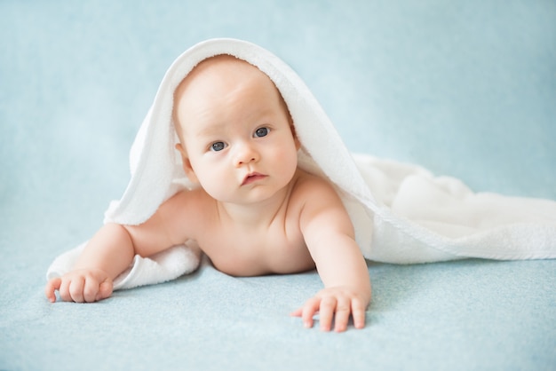 Bebê feliz com uma toalha depois do banho na cama em casa