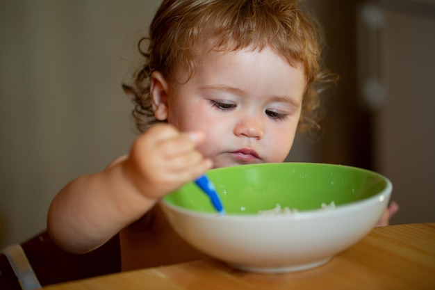 Bebê feliz comendo a si mesmo com uma colher conceito de nutrição infantil