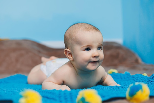 Un bebé feliz de cuatro meses yace sobre una manta tejida Retrato de bebé niño sosteniendo su cabeza
