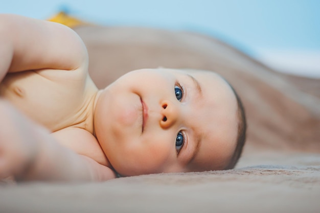 Un bebé feliz de cuatro meses yace sobre una manta tejida Retrato de bebé niño sosteniendo su cabeza