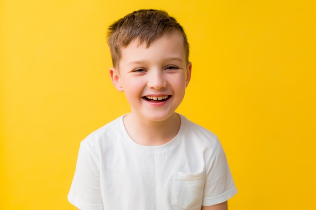 Bebê feliz de 7 anos em uma camiseta branca sobre um fundo amarelo