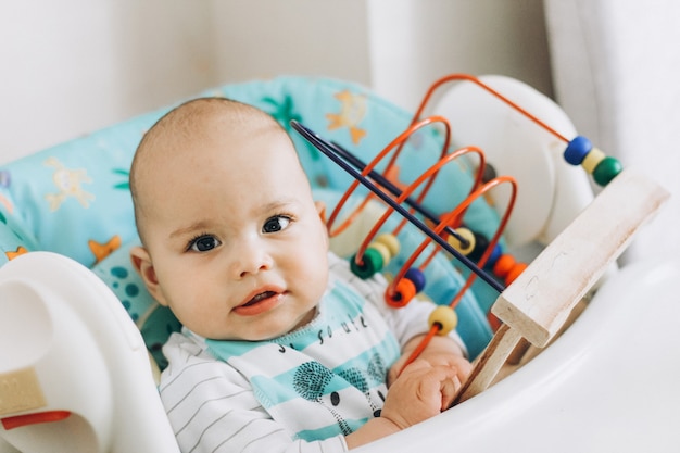 Bebé feliz e sorridente a brincar numa cadeira alta em casa