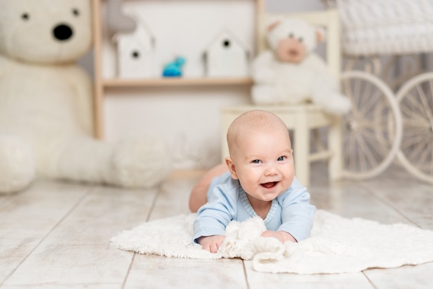 Bebê feliz fica em casa no quarto das crianças com brinquedos, conceito de desenvolvimento e jogos