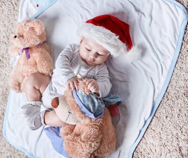 Bebé feliz con gorro de Papá Noel con peluches