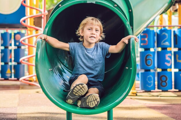 Bebé feliz lindo divertido que juega en el patio de recreo. La emoción de la felicidad, la diversión, la alegría.