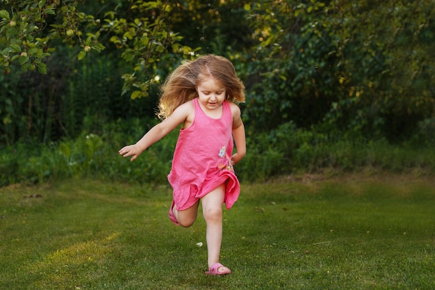 Bebé feliz niña sonriente corriendo en una puesta de sol al aire libre