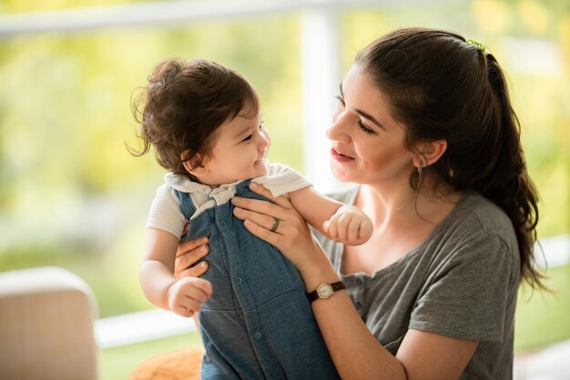 Bebé feliz del niño del hijo que juega en casa apoyando con el padre y la madre de la familia