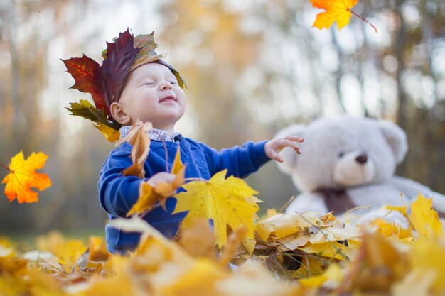 Bebé feliz en el parque de otoño juega con hojas