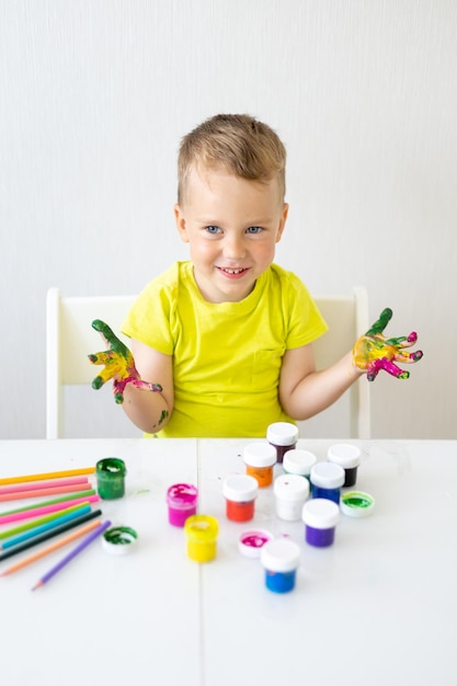 Bebê feliz que a criança desenha com os dedos com sorrisos de cores brilhantes