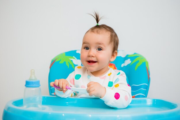 Bebé feliz sentado en una silla alta aislada sobre fondo blanco