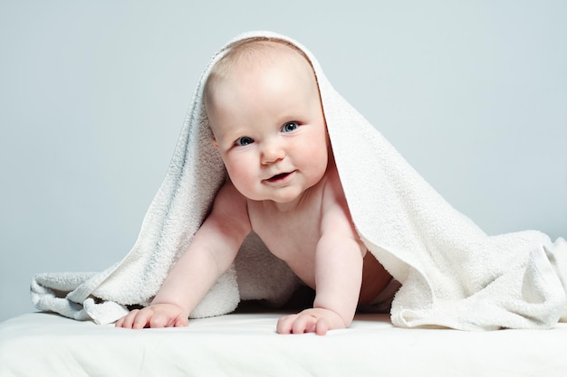 Bebé feliz en toalla blanca sobre fondo, concepto de cuidado parental