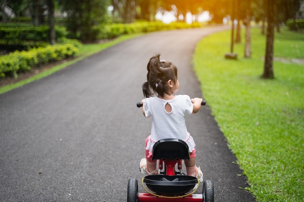 Bebê fofo andando de bicicleta no jardim