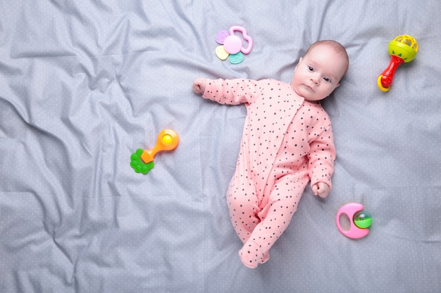 Bebê fofo brincando com brinquedo colorido chocalho. filho recém-nascido, menina, olhando para a câmera e rastejando.