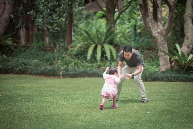 Bebê fofo brincando com o pai no jardim