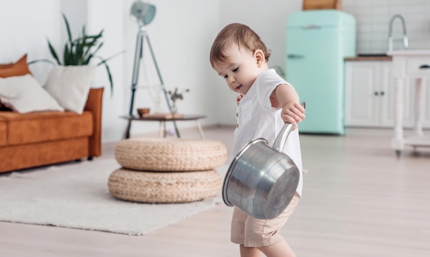 Bebê fofo brincando com utensílios de cozinha menino brincalhão de um ano segurando potes