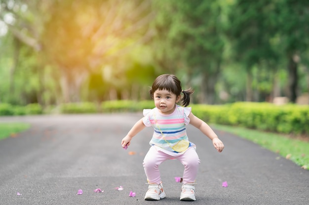 Bebê fofo brincando e pulando no jardim, conceito de atividade ao ar livre de bebê fofo