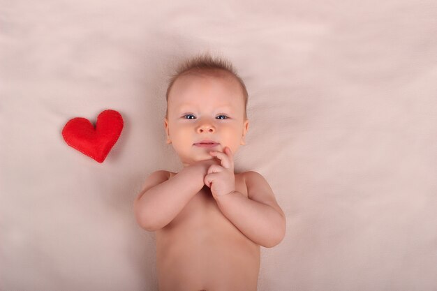 Bebê fofo com coração vermelho de brinquedo. Amor e conceito de família