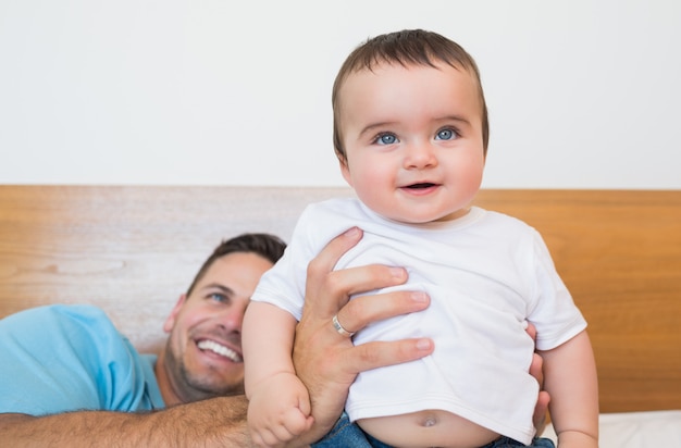 Bebê fofo com o pai na cama