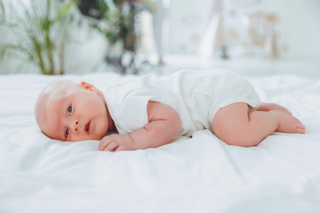 Bebê fofo de 2 meses deitado na cama roupa de cama natural pele delicada do bebê