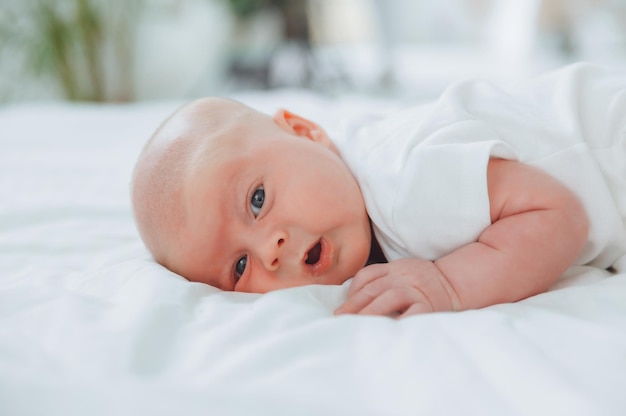 Bebê fofo de 2 meses deitado na cama roupa de cama natural pele delicada do bebê