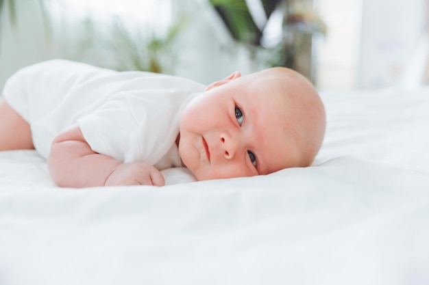 Bebê fofo de 2 meses deitado na cama roupa de cama natural pele delicada do bebê