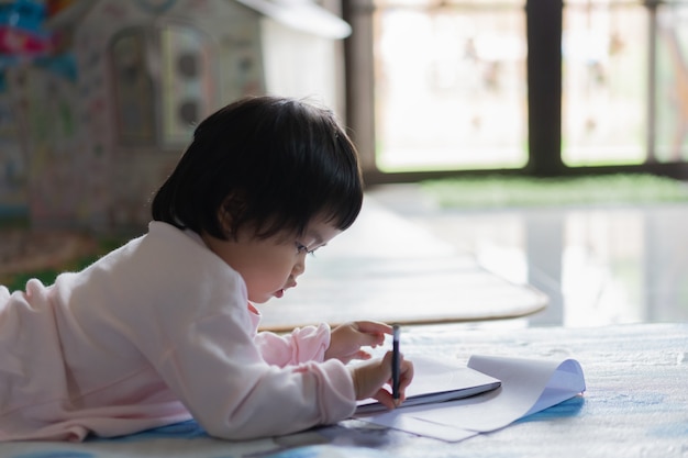 Bebê fofo desenhando no caderno no chão